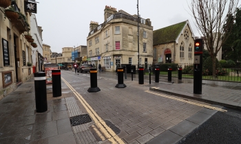 Black bollards with red and yellow bands on a paved street