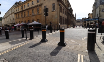 Black bollards with red, white and yellow bands on a paved street