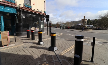 Black bollards with red, white and yellow bands on a paved street